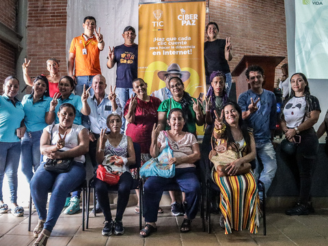 Grupo de personas sonriendo frente a la cámara en medio de un evento de Ciberpaz
