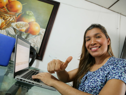 Mujer sonríe mientras usa su computador
