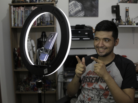 Hombre creando contenido para redes sociales, sonríe frente a la cámara de su celular